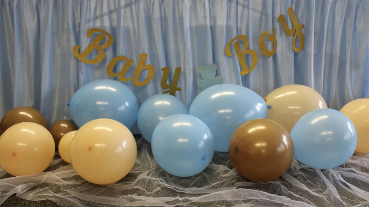 Globos celestes y dorados bajo un letrero de «Baby Boy» en un baby shower