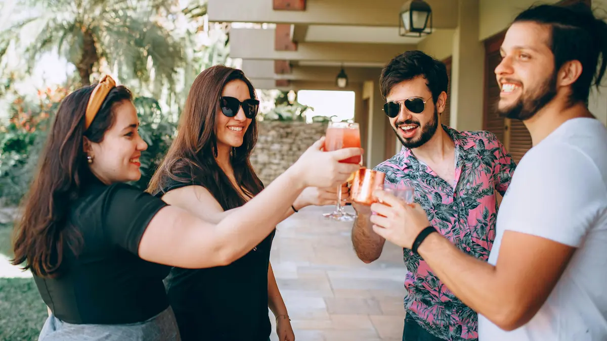 Un grupo de amigos brinda con tragos en una fiesta al aire libre