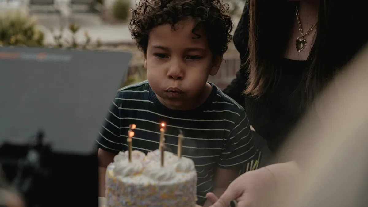 Un niño sopla las velas de su torta de cumpleaños