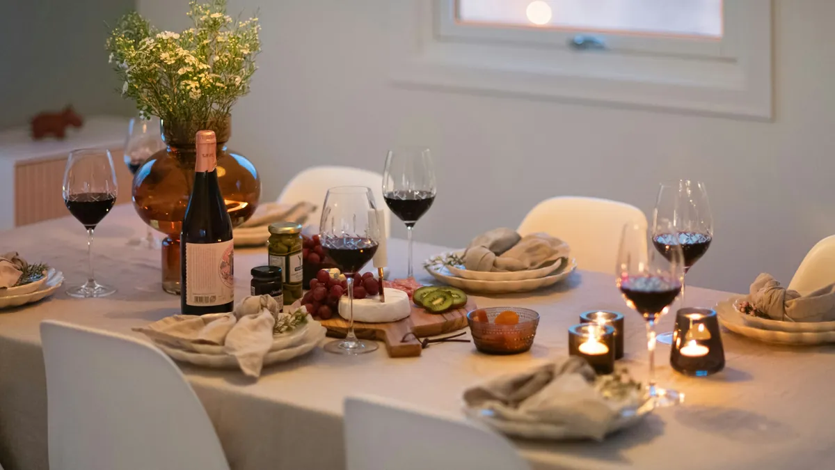 Una mesa puesta en casa con flores, velas, copas de vino y piqueos
