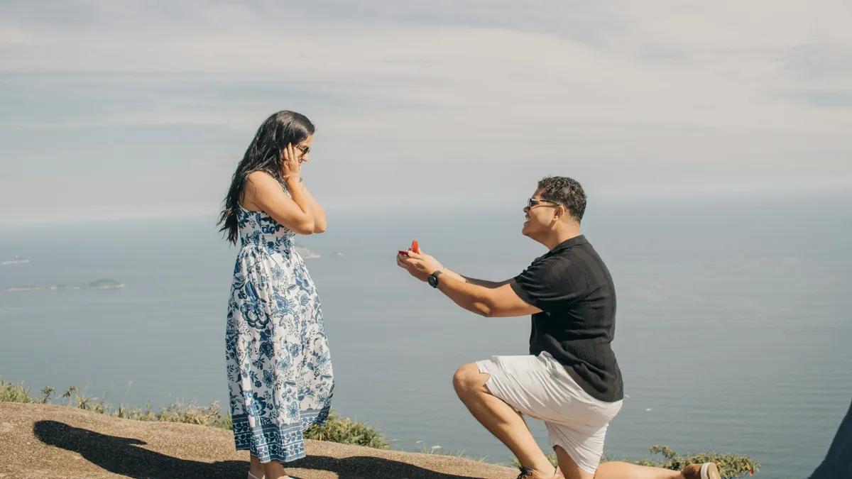 Él se arrodilla con el anillo frente al mar y ella se cubre el rostro de emoción
