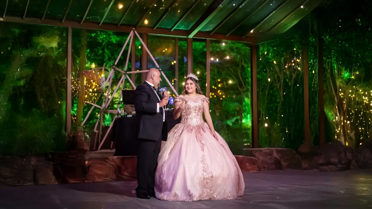 La quinceañera, con vestido rosado, baila el vals con su papá bajo las luces