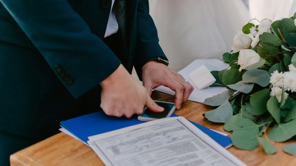 El novio sostiene el acta de matrimonio civil sobre la mesa, junto a un arreglo de flores