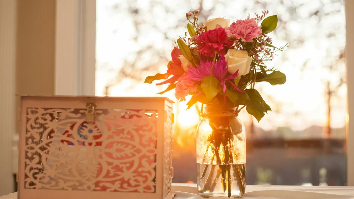 Una caja calada para sobres junto a un florero al atardecer