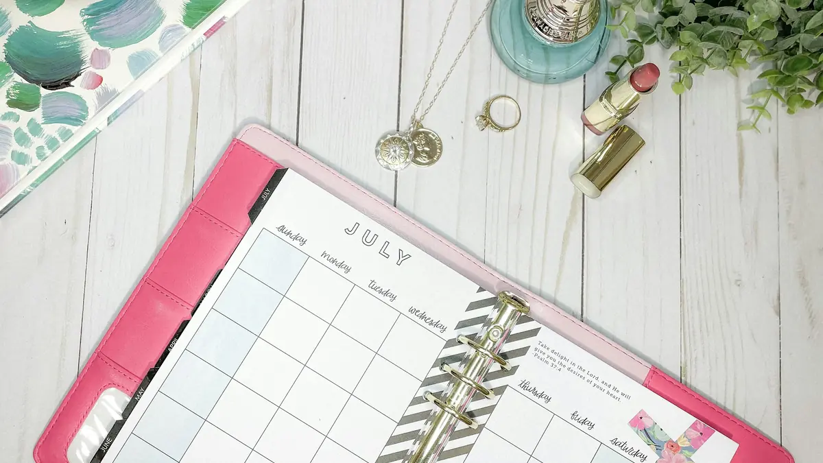 Una agenda rosada abierta en el calendario del mes