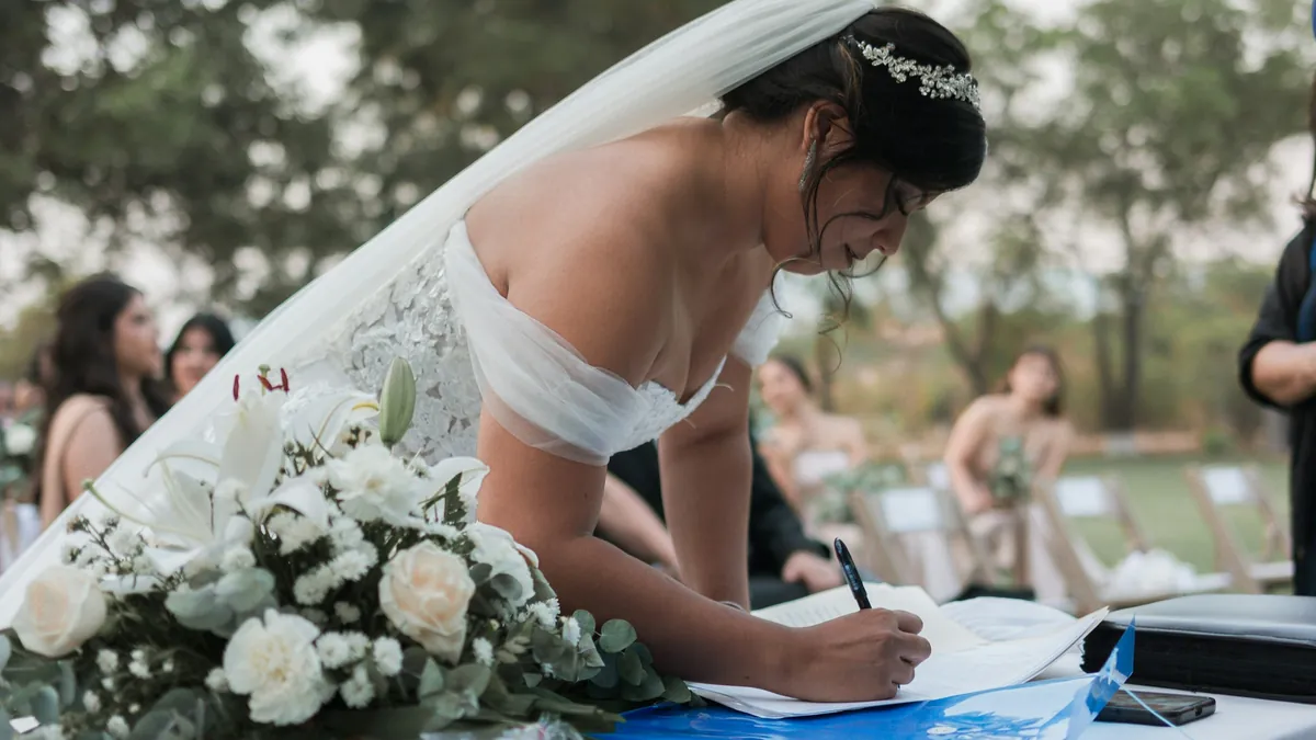 La novia firma el acta de matrimonio en una ceremonia al aire libre