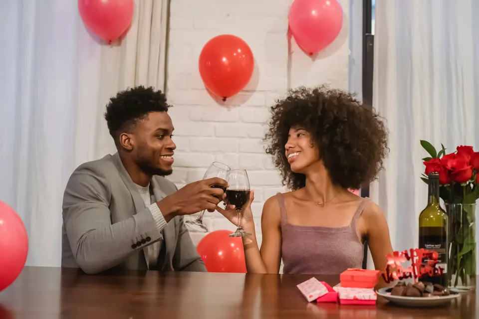 Una pareja brinda con copas de vino en una mesa decorada con globos