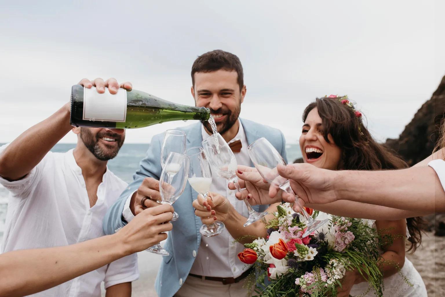 Un brindis en una boda al aire libre: sirven champán en una fila de copas mientras los novios ríen