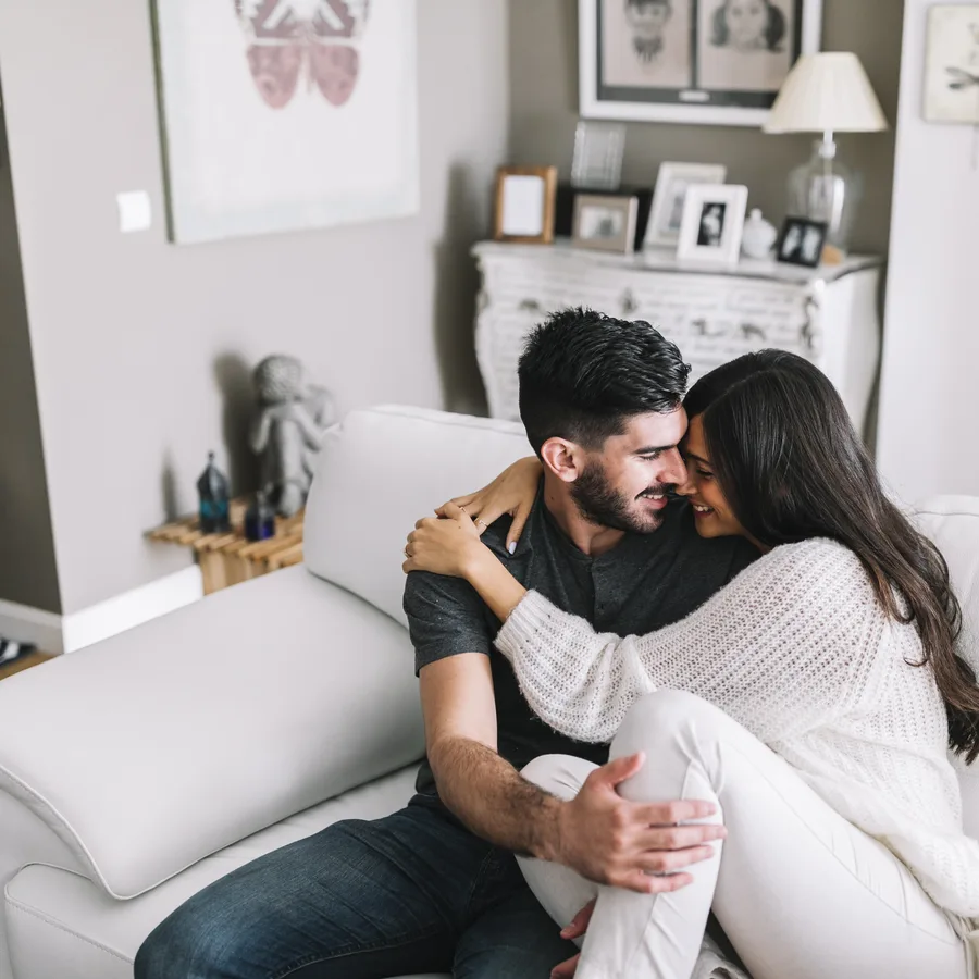 Una pareja abrazada en el sofá de su departamento