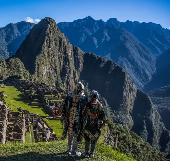 Una pareja con ponchos contempla Machu Picchu