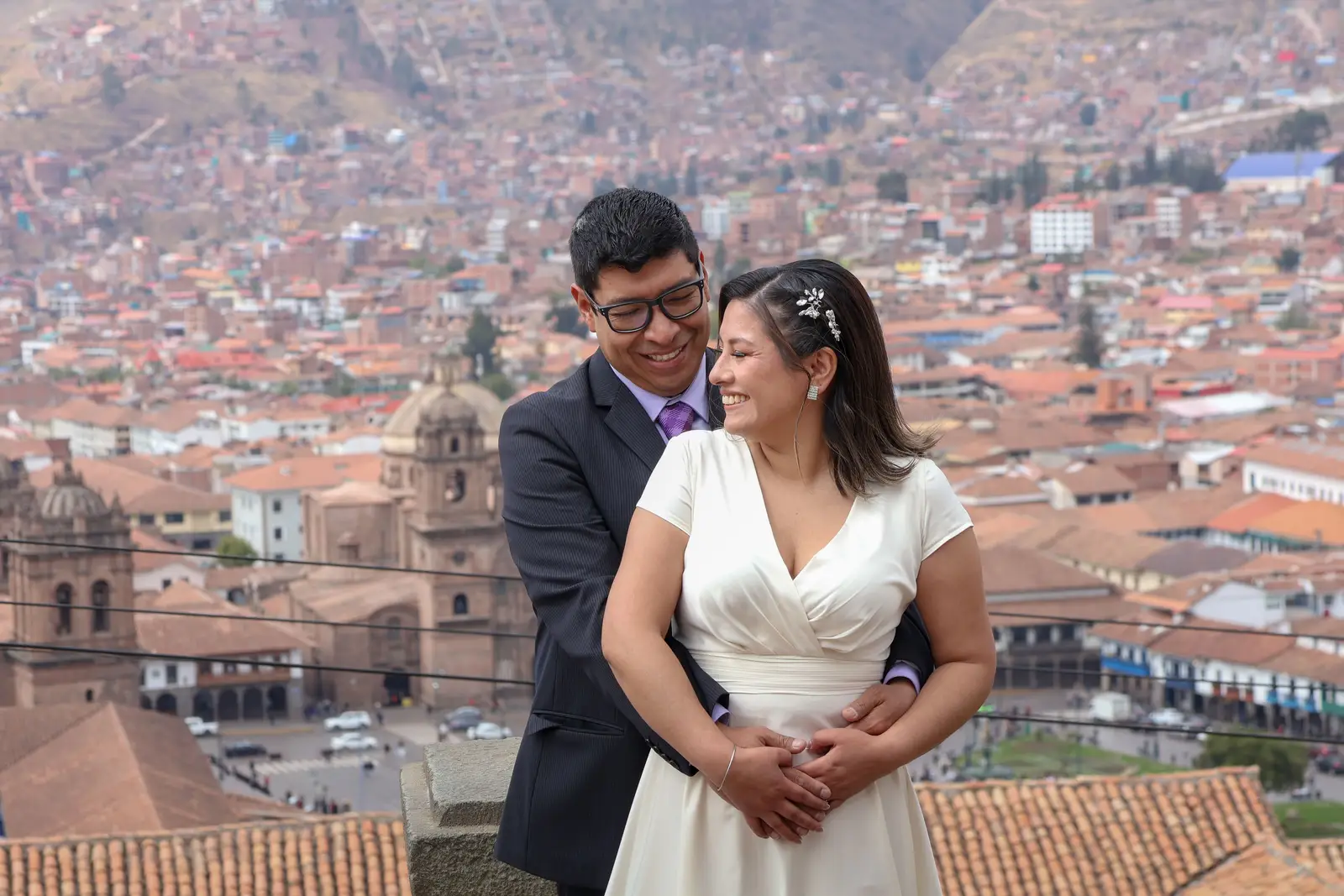 A bride and groom embracing at a lookout over Cusco