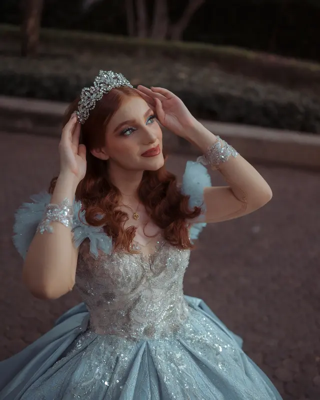 Young woman wearing a tiara and blue gown beside steps